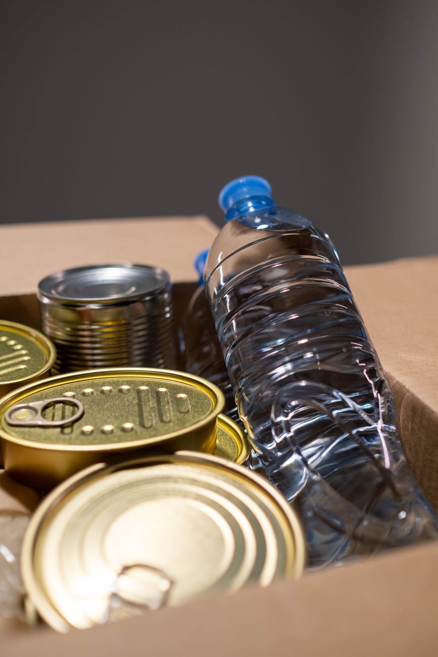 canned food and bottle of water in a carton box